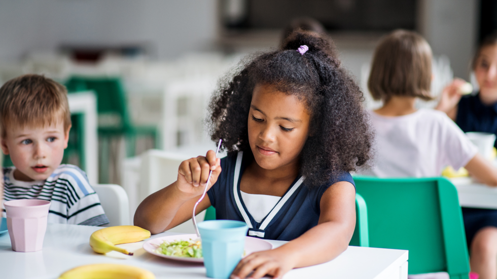 Criança um prato de salada, representando a importância da alimentação saudável na educação infantil.