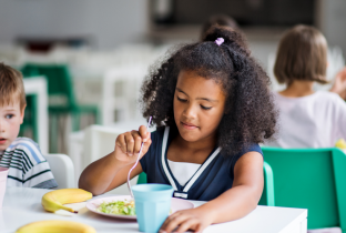 Criança um prato de salada, representando a importância da alimentação saudável na educação infantil.