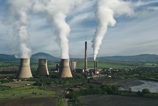 Usinas termelétricas em operação, emitindo vapor, representando geração de energia não renovável.